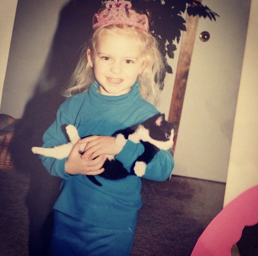 heather as a kid, wearing a pink tiara and holding a cat